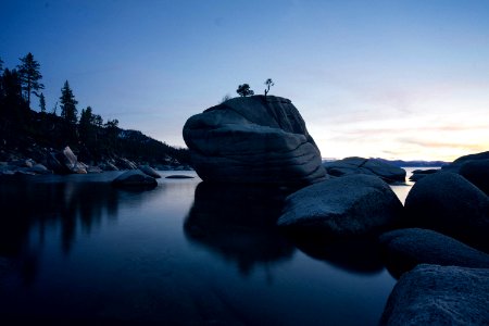 rock formation on body of water at sunset photo