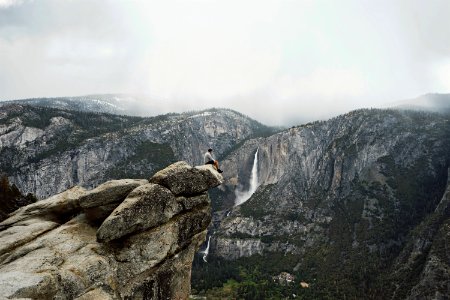 person sitting on mountain cliff photo