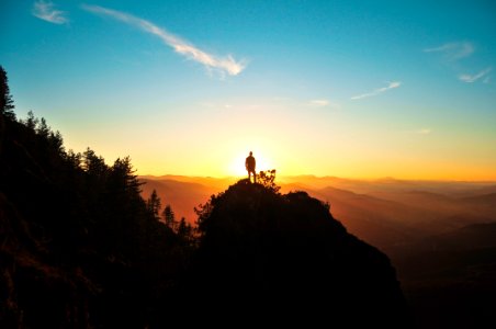 silhouette of man standing on mountain peak photo