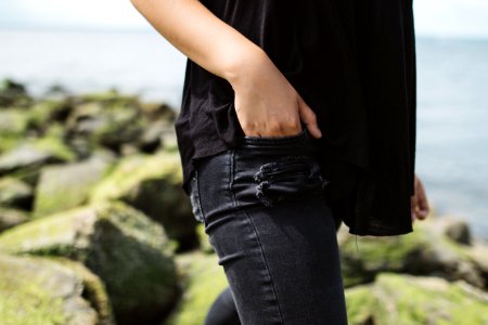 person wearing black denim bottoms near on body of water during daytime photo