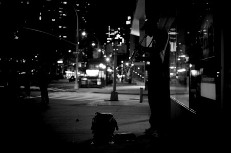 grayscale photography of man playing musical instrument beside road photo