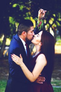 man and woman kissing near trees photo