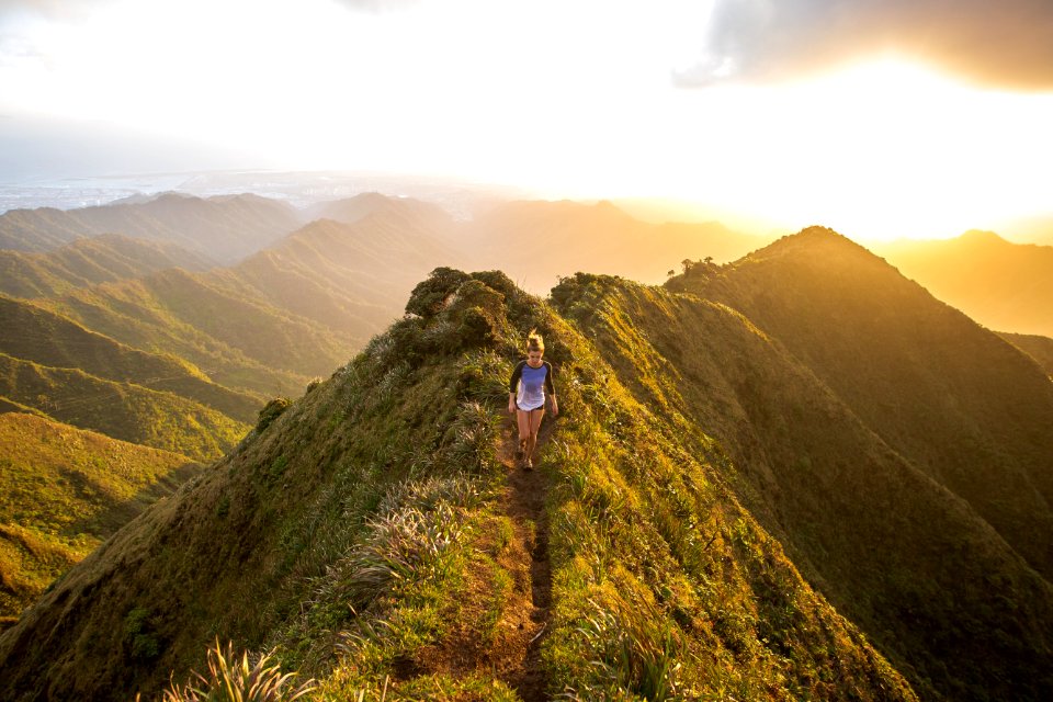 woman walking on pathway on top of hill at golden hour