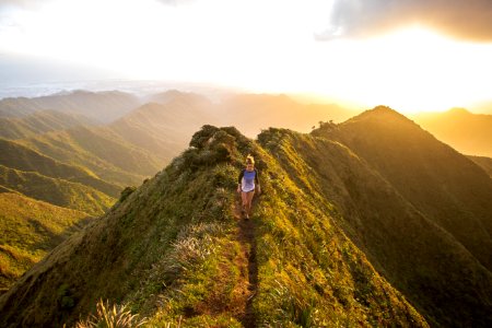 woman walking on pathway on top of hill at golden hour photo