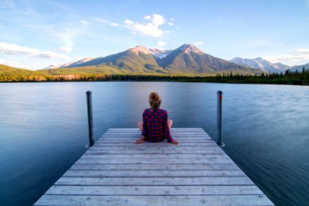 woman sitting on dock bridge near lake during daytime photo