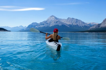 woman wearing red hat riding on white kayak facing mountain alps photo