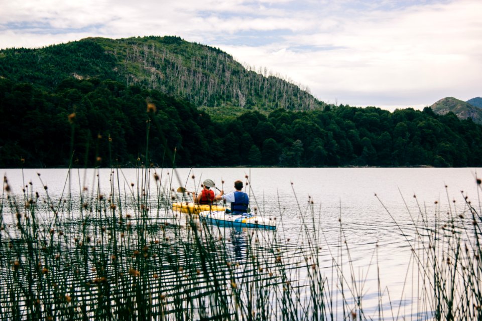 two person kayaking near mountain