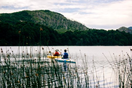 two person kayaking near mountain photo