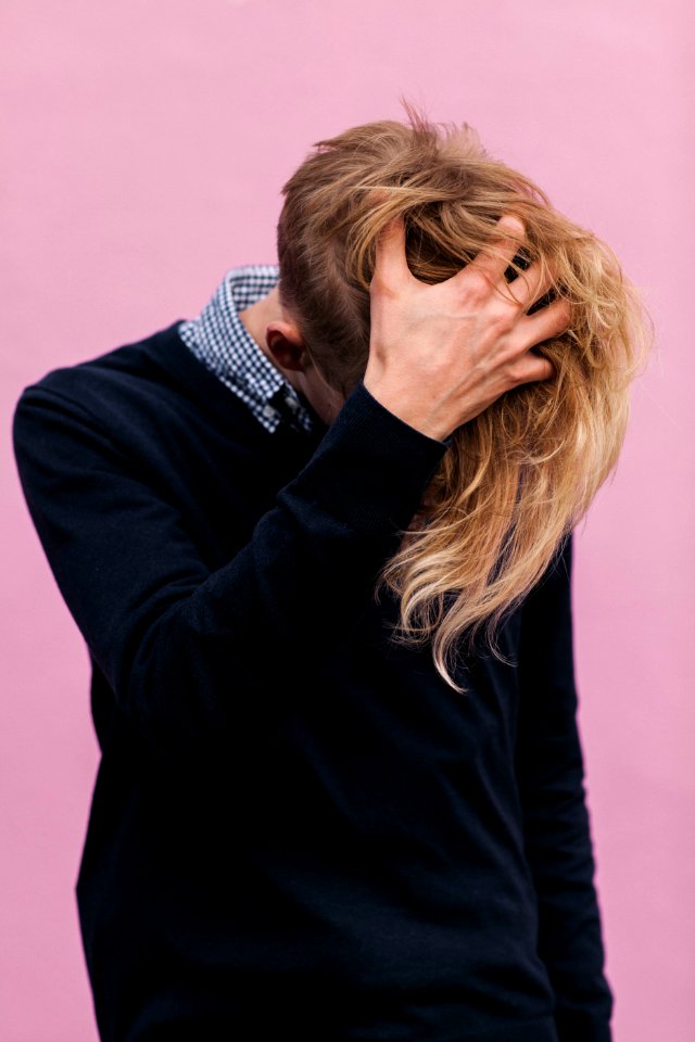 man wearing black crew-neck sweatshirt with hand running through hair