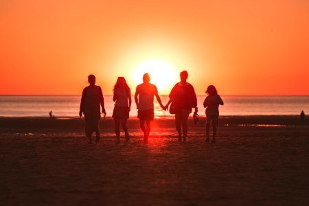 silhouette photo of five person walking on seashore during golden hour photo