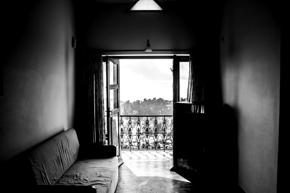 greyscale photgraphy of fabric sofa beside wall inside the building