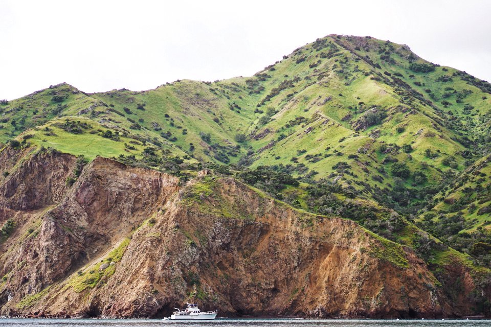 green mountain near body of water with white watercraft during daytime photo