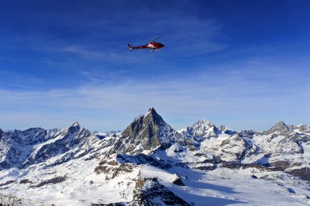 photo of red helicopter flying in snowy mountain photo