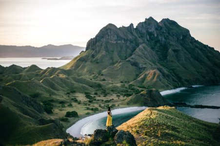 woman standing on mountain near body of water photo