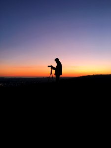 silhouette of man in front of DSLR camera during golden hour photo