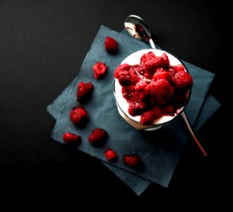bowl of red strawberries beside silver spoon photo