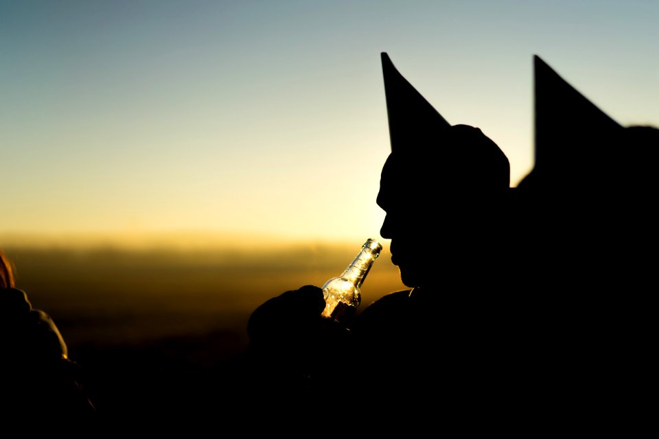 silhouette of person holding bottle during orange sunset