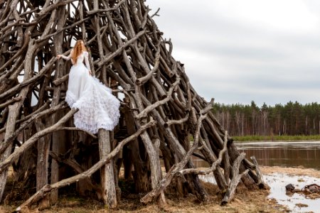 woman in white dress on piled wood logs photo