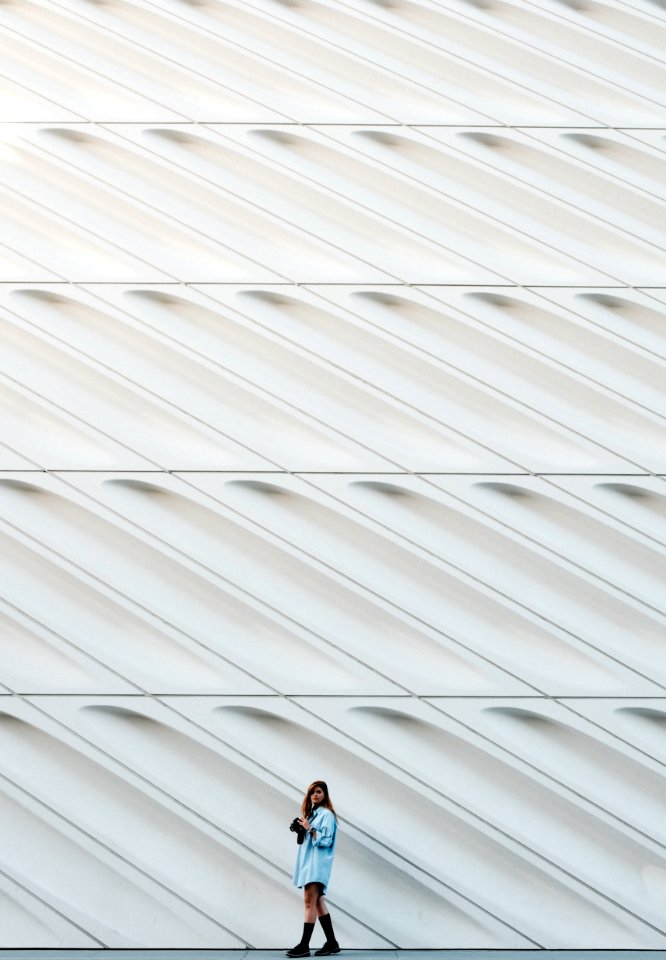 woman standing beside white concrete wall