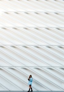 woman standing beside white concrete wall photo