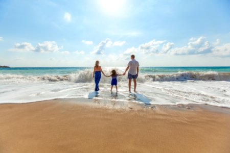 man, woman and child holding hands on seashore photo