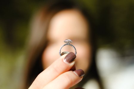 shallow focus photography of woman holding a diamond ring photo