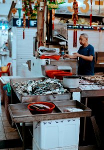 man filling clear plastic bottle near storefront photo