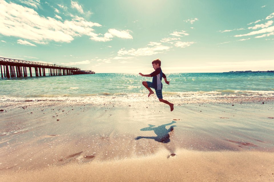 boy in wetsuit jumping on shore