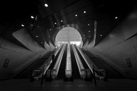 grayscale photography of person on escalator