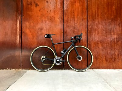 black road bike parked beside brown wooden wall photo