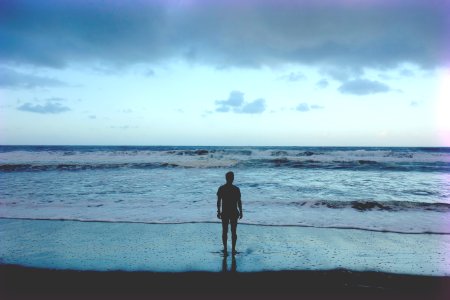 silhouette photography of man standing on seashore photo