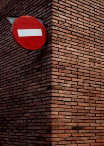red and white signage on red brick wall at daytime photo