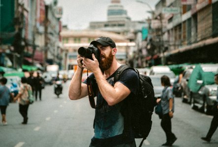 shallow focus photography of man using a DSLR camera photo