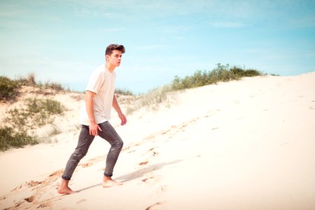 man wearing white t-shirt standing on sand field during daytime photo