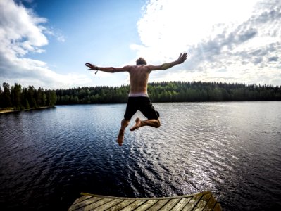 man jumping through body of water photo