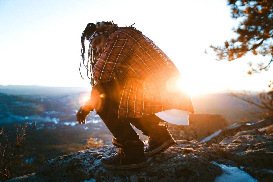man sitting on rock near cliff