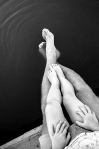 grayscale photo of person's feet on body of water photo