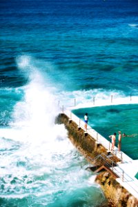 people standing beside pool next to the sea photo