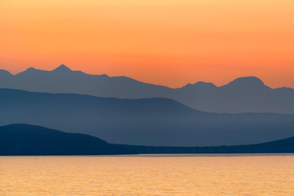 silhouette of mountains near body of water during golden hour photo