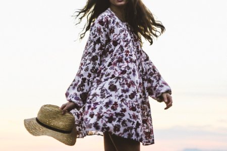 woman wearing white and brown floral long-sleeved shirt while holding brown fedora hat photo