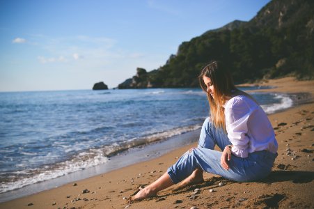 woman sitting on beach shore during daytime photo