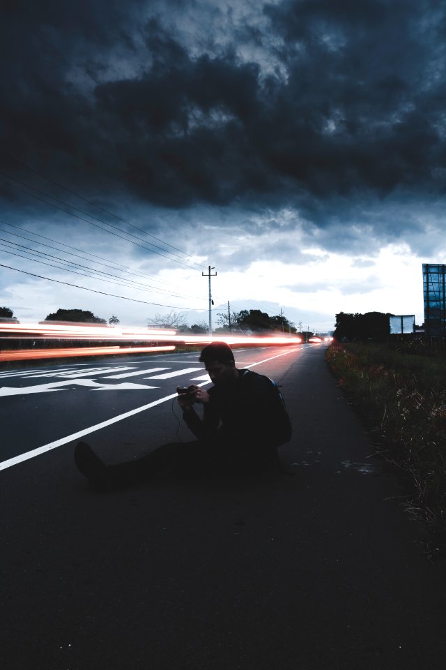 man sitting on road in time lapse photography
