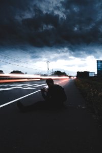 man sitting on road in time lapse photography