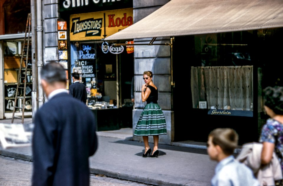 woman looking left while standing beside store along the road