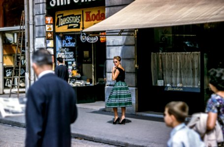 woman looking left while standing beside store along the road