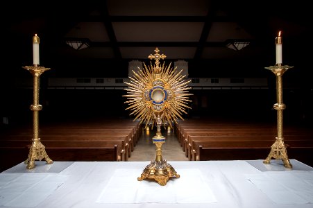 Gold colored religious objects and candles on a table at the front of a church aisle. photo