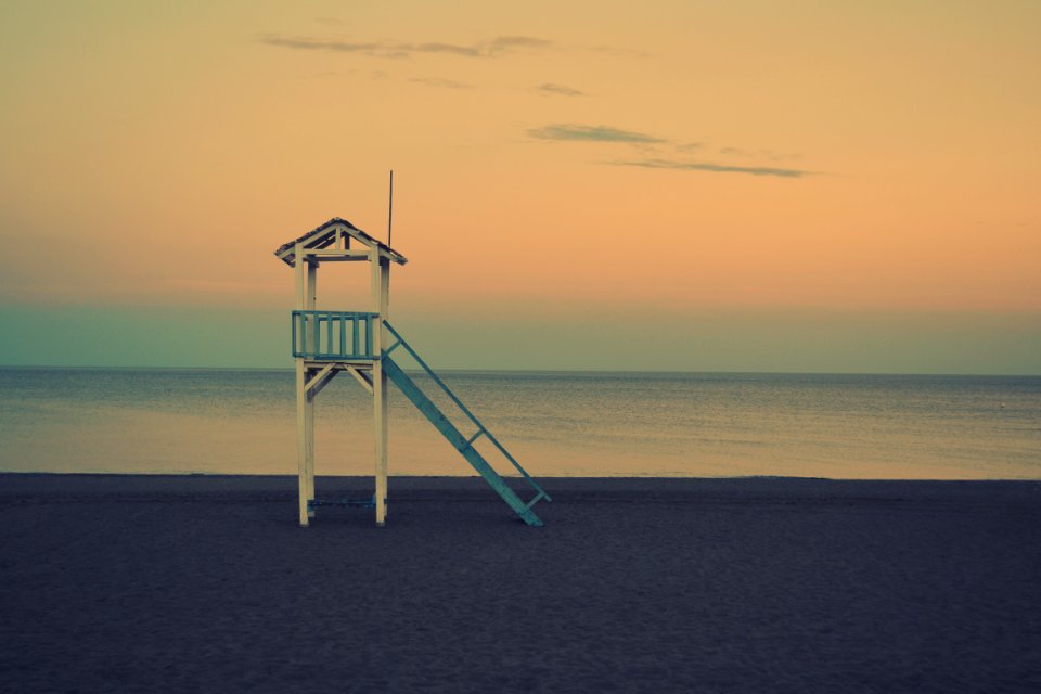white wooden lifeguard station near seashore at golden hour photo