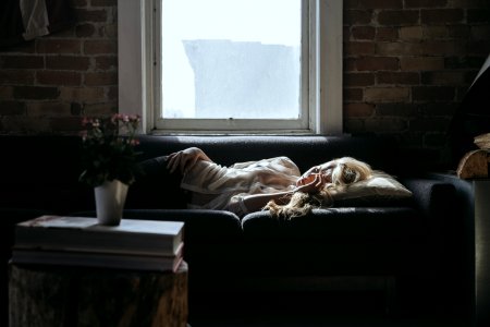woman lying on sofa near closed window during daytime photo