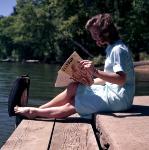 woman sitting while reading near body of water photo