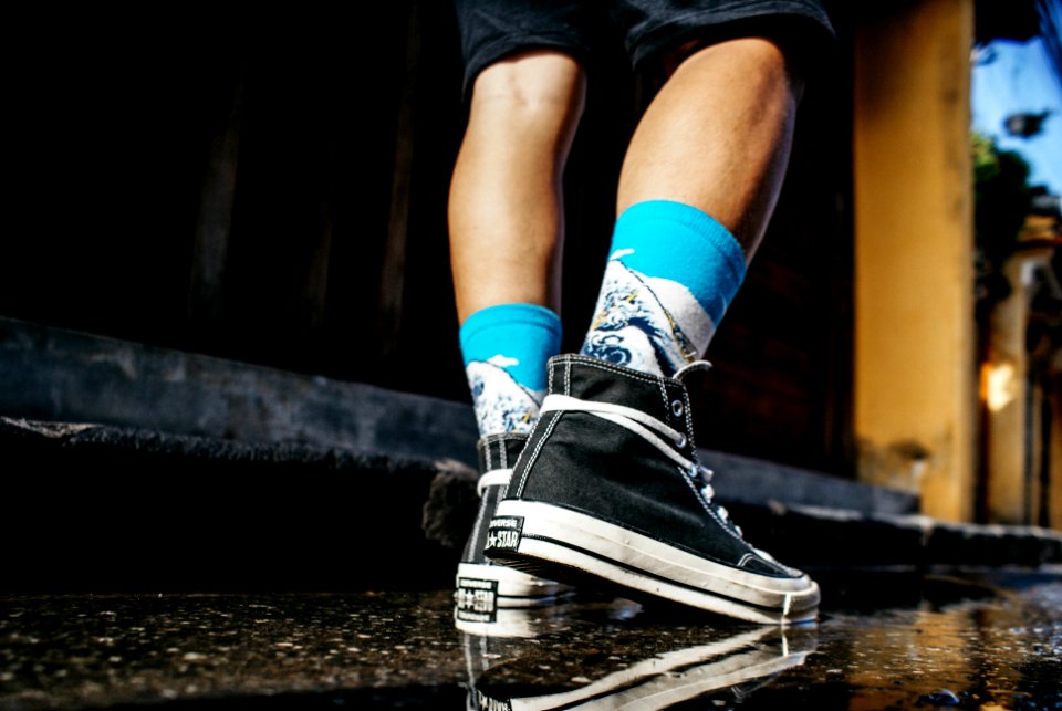man wearing black high-tops walking on wet road